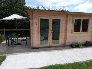 a small wooden cabin with a table and an umbrella at Cosy cabin for two in Truro