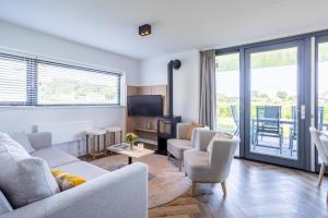 a living room with a couch and chairs and a tv at Duyndomein Noordwijk in Noordwijk