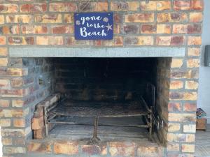 a brick fireplace with a sign that says come to the beach at Strandfontein holiday house in Strandfontein