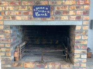 una chimenea de ladrillo con un cartel que dice ven a la playa en Strandfontein holiday house, en Strandfontein