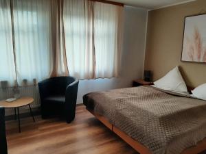ein Hotelzimmer mit einem Bett, einem Stuhl und einem Tisch in der Unterkunft Altes Bootshaus in Torgau