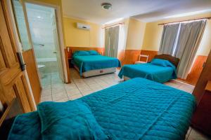 a hotel room with two beds and a bathroom at Hotel Montecarlo in Caldera