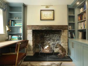 a fireplace in a room with a desk and book shelves at Grove Cottage in Salperton