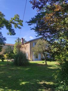 uma casa num quintal com árvores em primeiro plano em Le Fournil des Jardins d'Ayaël em Ozenay