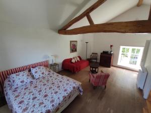 a bedroom with a bed and a red couch at Le Fournil des Jardins d'Ayaël in Ozenay