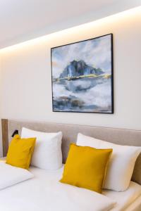 uma cama com almofadas amarelas e um quadro na parede em Hotel TwentyFour Living em Bad Urach