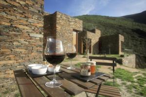 two glasses of red wine sitting on a wooden table at InXisto Lodges in Piódão