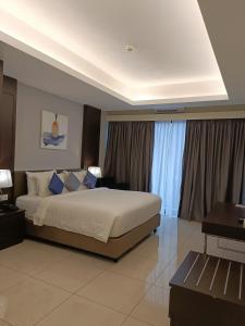 a bedroom with a large bed and a desk and curtains at MagTree Genting Highlands in Genting Highlands