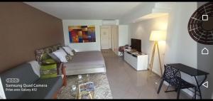 a room with a bed and a desk and a television at Grand studio les pieds dans l'eau, centre ville in Le Gosier
