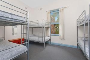 a room with three bunk beds and a window at PodBed Sydney in Sydney
