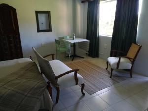 1 dormitorio con 1 cama, 2 sillas y mesa en Crossroads Guestrooms en Gordonʼs Bay