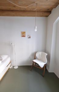 une chambre blanche avec une chaise et une lampe dans l'établissement HERZIGE WOHNUNG IN ALTEM GEMÄUER, à Linz