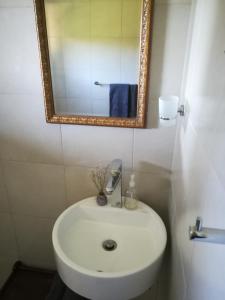 a bathroom with a white sink and a mirror at Crossroads Guestrooms in Gordonʼs Bay
