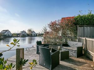 a patio with chairs and a couch next to a body of water at Detached vacation home in Friesland with waterfront views in Grou