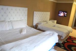a hotel room with two beds and a tv at Royal Nest Guest House in Vereeniging