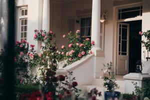 a white house with flowers on the steps at Les Chambres Guest House in Franschhoek