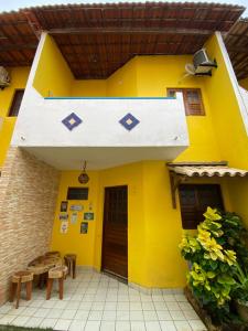 una casa amarilla con una mesa y un banco en Duplex em condomínio no Barra Mar, en Barra de São Miguel