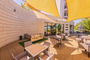 a patio with tables and chairs and a building at Vital Hotel Nautis in Gárdony