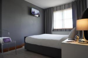 um quarto de hotel com uma cama e uma televisão na parede em VIP@TheMeadows em Portadown