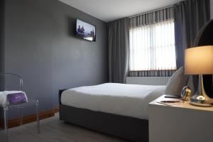 a hotel room with a bed and a tv on the wall at VIP@TheMeadows in Portadown
