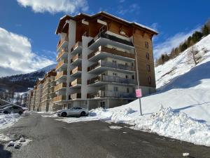 a large building with a car parked in the snow at 3 pièces la Foux d Allos vue montagne et station in La Foux