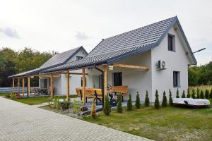 une petite maison blanche avec un toit en métal dans l'établissement Zatoka Perska - dom GREK nad jeziorem Tarnobrzeskim, à Tarnobrzeg