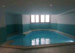 een groot zwembad in een kamer met blauwe tegels bij Bel appartement lumineux au pied des pistes in Valmeinier