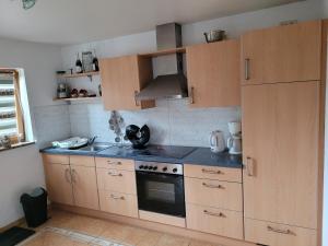 HeidenburgにあるSchöne gemütliche Ferienwohnung im Hunsrückの木製のキャビネットとコンロ付きオーブンを備えたキッチン