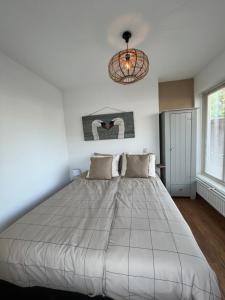 a large bed in a bedroom with a chandelier at 't Zwanennest Egmond aan Zee in Egmond aan Zee