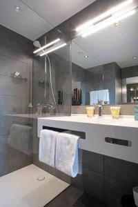 a bathroom with a sink and a shower with a mirror at RiKu HOTEL Reutlingen in Reutlingen