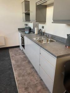 a kitchen with white cabinets and a sink at Studio Apartment Harlow in Potter Street