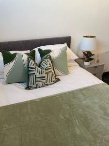 a bed with green and white pillows on it at Studio Apartment Harlow in Potter Street