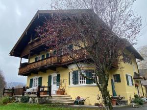 a large yellow house with a wooden roof at Edle Altbauwohnung trifft oberbayrisches Bergidyll in Bayrischzell