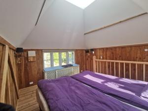 1 dormitorio con cama morada y ventana en Birkevang The Silo - Rural refuge, en Faxe