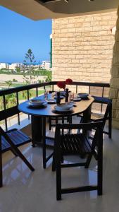 una mesa y sillas en un balcón con vistas al océano en Green Beach Apartment, en El Alamein