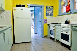a kitchen with yellow walls and a white refrigerator at PodBed Sydney in Sydney