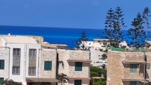 un gruppo di edifici con l'oceano sullo sfondo di Green Beach Apartment a El Alamein