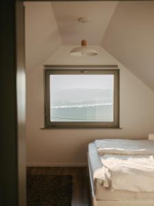 Una ventana en una habitación con cama y el océano en Hegyi Kabin - Zebegény, en Zebegény