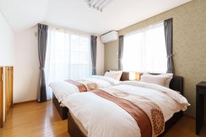 2 Betten in einem Zimmer mit großen Fenstern in der Unterkunft Luxury Guest House in Tokyo Shinjuku in Tokio