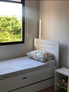 Cama con almohada y ventana en una habitación en Casa Mag :) en Río de Janeiro