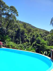 a swimming pool with a mountain in the background at Acqua Jungle Glamping & Room in Abraão