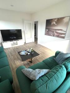 a living room with a green couch and a tv at Ferien-Whg Stünkel nähe Steinhuder Meer in Steinhude