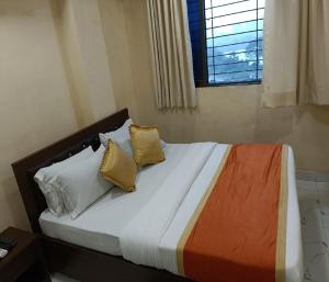 ein Schlafzimmer mit einem Bett mit Kissen und einem Fenster in der Unterkunft Hotel Royal Residency in Navi Mumbai