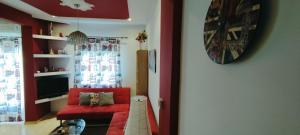 un salon avec une chaise rouge et une télévision dans l'établissement Kelly's Luxury Suite in Thessaloniki's Center, à Thessalonique