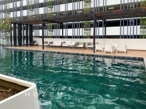 a pool in a building with chairs and water at Comfort Pool View Studio 5PX Near Mid Valley in Kuala Lumpur