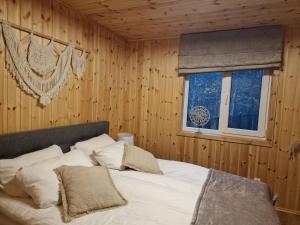 a bed in a wooden room with a window at Svečių namai Banga in Paplatelė