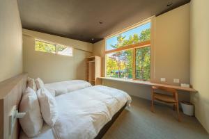 a bedroom with two beds and a desk and a window at Ren chalet in Hakuba