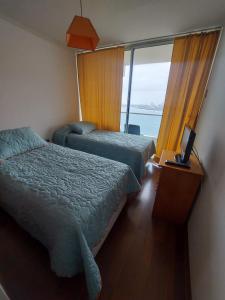 Habitación de hotel con 2 camas y ventana en Departamentos Nautilus en Iquique
