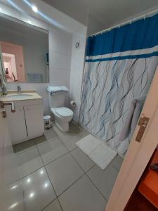 y baño con aseo y cortina de ducha. en Departamentos Nautilus, en Iquique