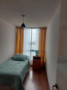 a small bedroom with a bed and a window at Departamentos Nautilus in Iquique